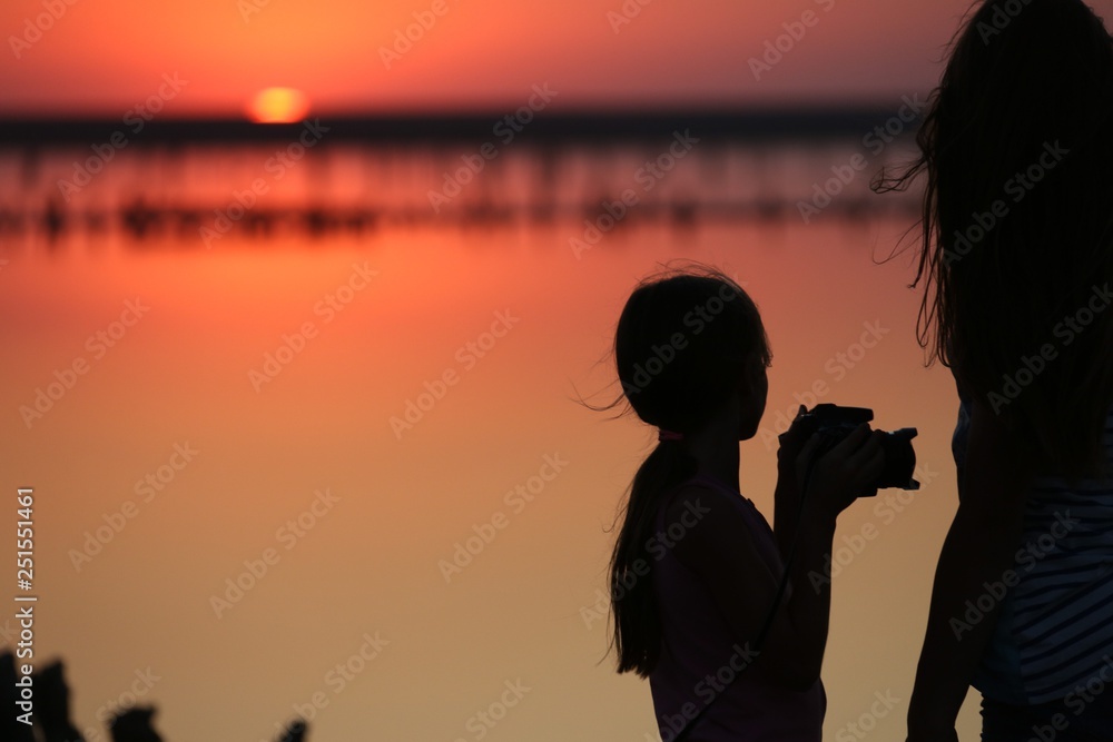 on a salt lake two girls are blurred against the background of the horizon, photographed at sunset and in summer