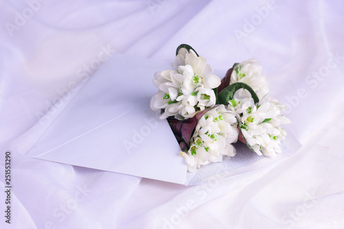 White wildflowers in envelope on white fabric background.  Romantic communication background concept mockup.