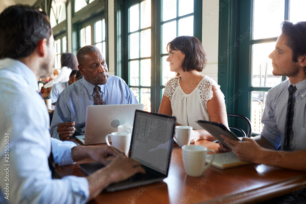Business Team Having Informal Meeting Around Table In Coffee Shop Business Team Having Informal Meeting Around Table In Coffee Shop