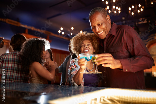 Portrait Of Senior Couple Drinking And Dancing In Bar Together