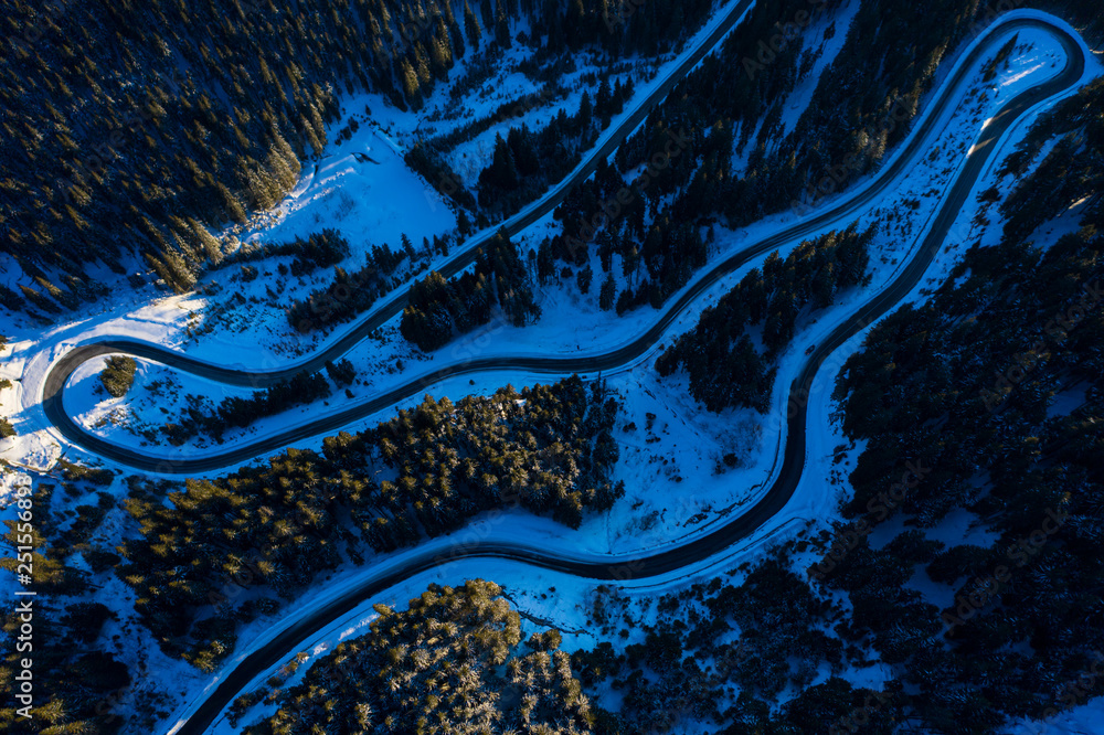 Aerial view of snowy forest with a road. Captured from above with a drone.