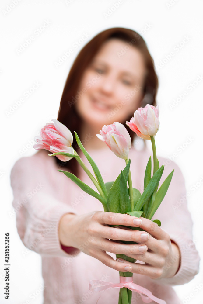 Young beautiful woman gives pink tulips on white background. Young beautiful woman gives pink tulips on white background.