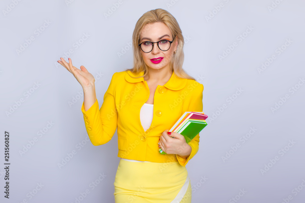 Woman in yellow suit holding books in her hands Woman in yellow suit holding books in her hands