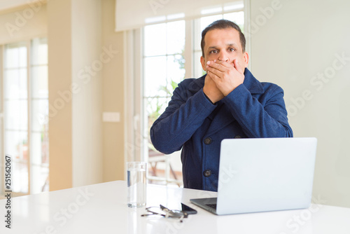 Middle age business man working using laptop shocked covering mouth with hands for mistake. Secret concept.