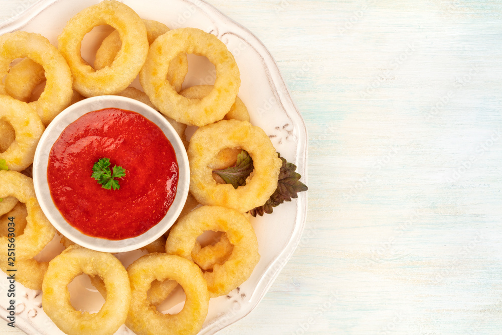 An overhead closeup photo of a plate of squid rings with a red sauce and a place for text