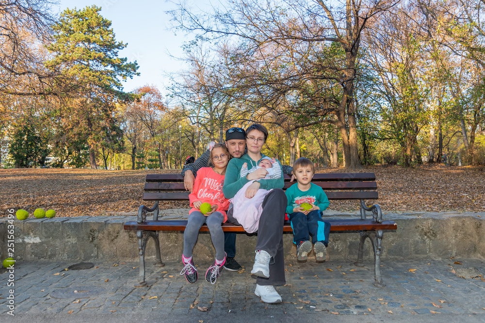 A family with three children sitting on the bench in the park