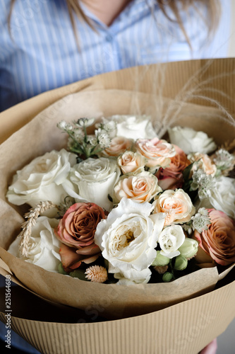 Bouquet of white and beige Roses. Woman Florist holding bouquet of Flowers indoor. Female florist preparing bouquet in flower shop. Close up. Mother s Day and Valentine s Day concept