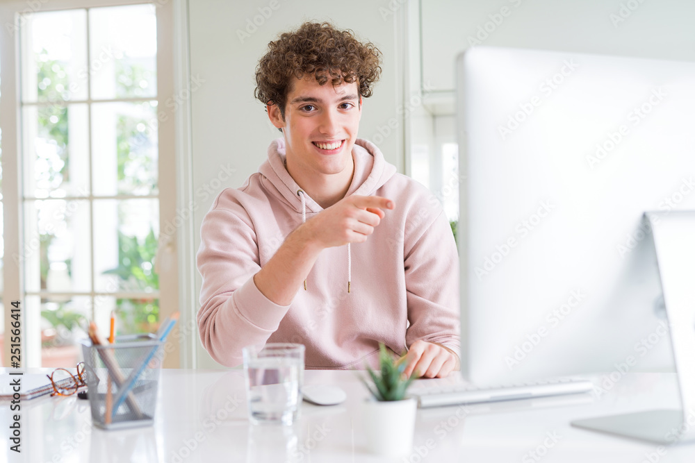 Young student man using computer very happy pointing with hand and finger