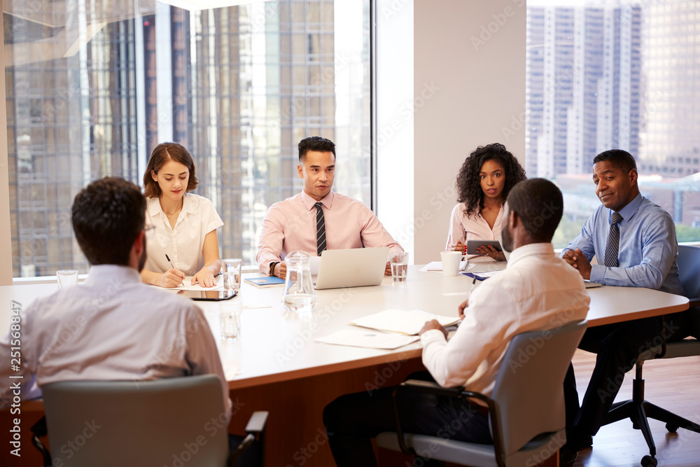 Fototapeta premium Group Of Business Professionals Meeting Around Table In Modern Office