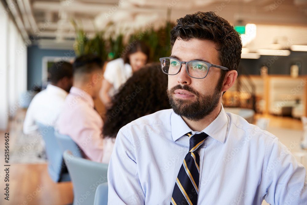 Businessman In Modern Office With Colleagues Meeting Around Table In Background Businessman In Modern Office With Colleagues Meeting Around Table In Background