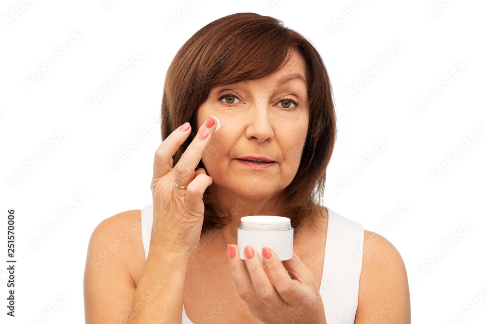 beauty, skincare and cosmetics concept - senior woman applying cream to her face beauty, skincare and cosmetics concept - senior woman applying cream to her face