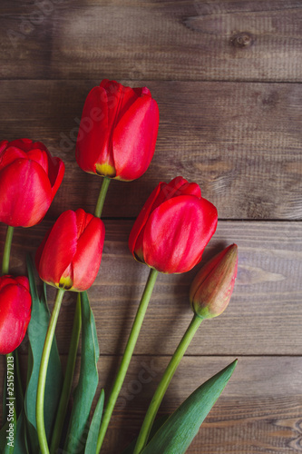 Row of red tulips on wooden background with space for message. Mother's Day background. Top view.