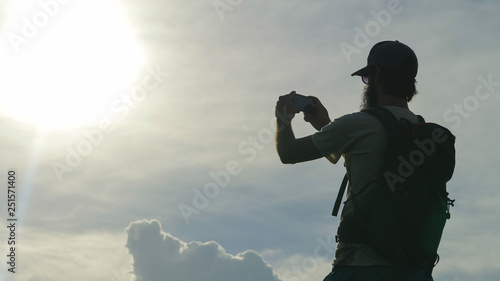 Tourist walking in nature photographing with smartphone