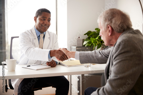 Senior Man Having Consultation With Male Doctor In Hospital Office