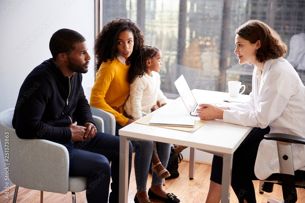 Family Having Consultation With Female Pediatrician In Hospital Office Family Having Consultation With Female Pediatrician In Hospital Office