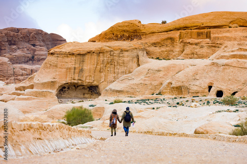 A couple of tourists are strolling through the beautiful ruins of Petra in Jordan. Petra is a historical and archaeological city in southern Jordan.