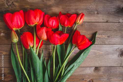 Row of red tulips on wooden background with space for message. Mother's Day background. Top view. Flat lay