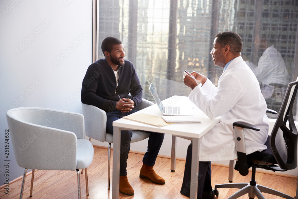 Man Having Consultation With Male Doctor In Hospital Office Man Having Consultation With Male Doctor In Hospital Office