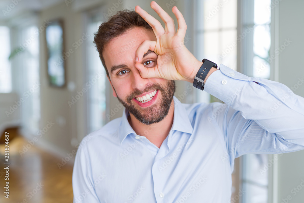 Obraz premium Handsome business man doing ok gesture with hand smiling, eye looking through fingers with happy face.