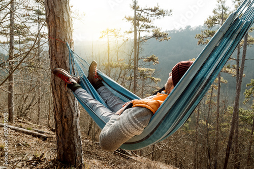 Young happy man relaxing lying in hammock on top of mountain. photo