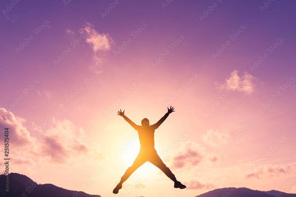 Happy man jumping at top of mountain with sunset sky abstract background.