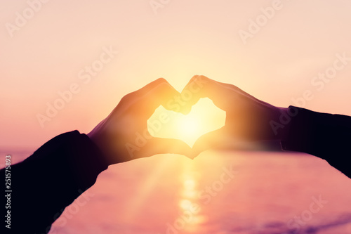 Female hands heart shape on nature bokeh sun light flare wave and blur tropical beach abstract background.