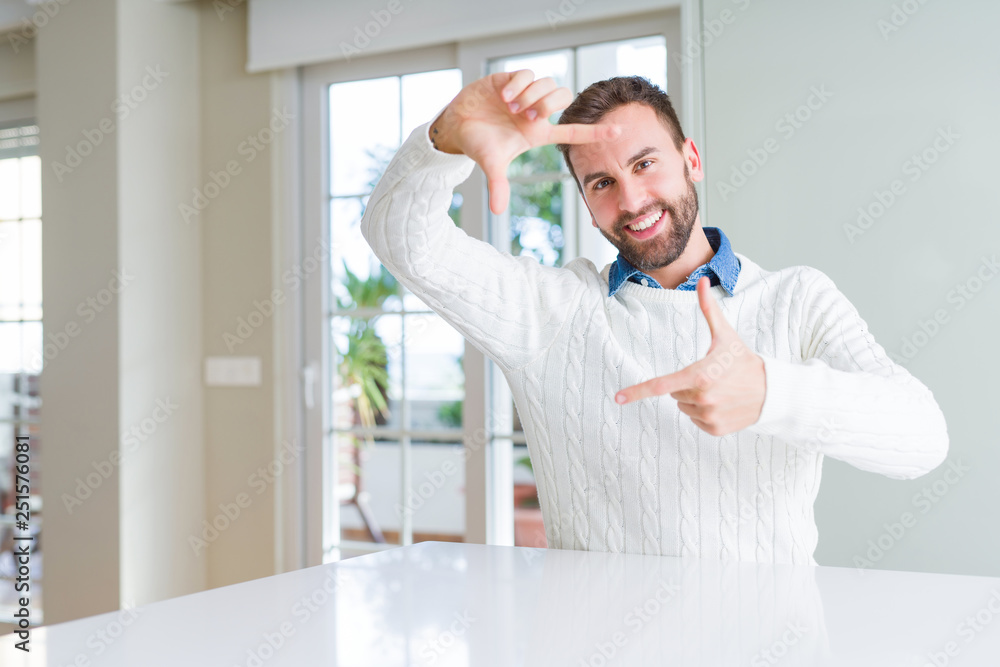 Fototapeta premium Handsome man wearing casual sweater smiling making frame with hands and fingers with happy face. Creativity and photography concept.