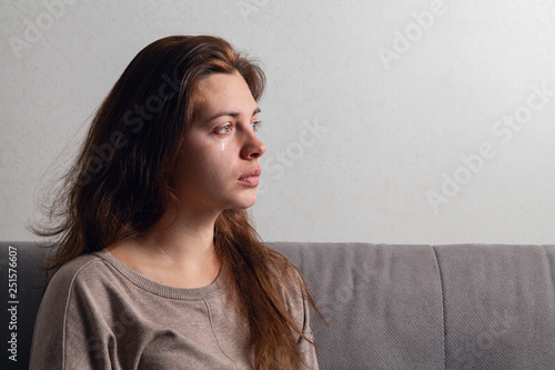 Foto The young woman is crying. Tears flow down her cheeks.