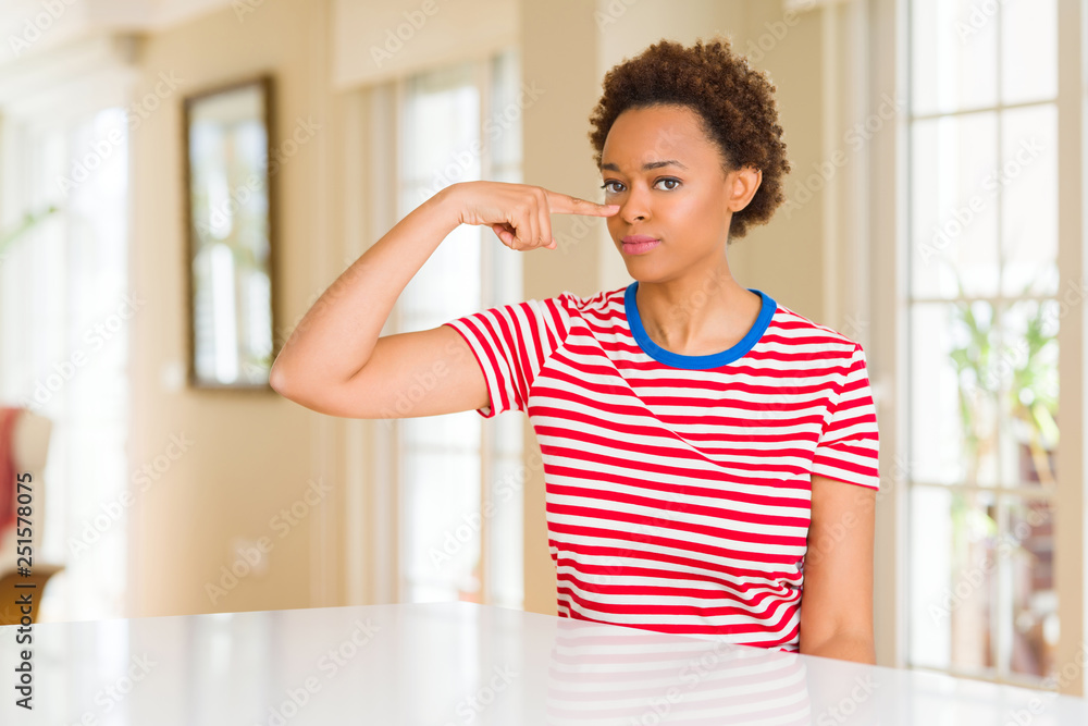 Young beautiful african american woman at home Pointing with hand finger to face and nose, smiling cheerful Young beautiful african american woman at home Pointing with hand finger to face and nose, smiling cheerful