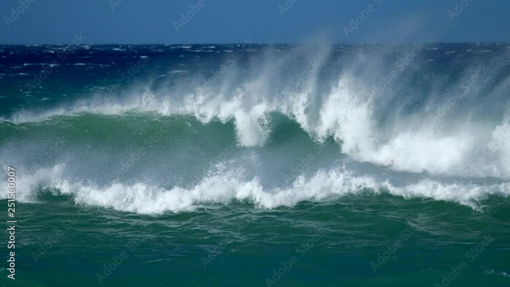 Ocean wave breaks with a lot of spray during windy weather Ocean wave breaks with a lot of spray during windy weather
