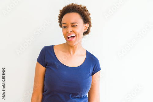 Young beautiful african american woman over white background winking looking at the camera with sexy expression, cheerful and happy face.