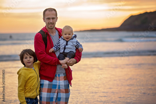 Young father with his beautiful children, enjoying the sunset over the ocean on a low tide in Devon