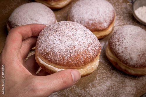 hand taking tasty donut from dark table.