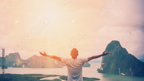 Feel good freedom and travel adventure concept. Copy space of happy man raise hands on  top of mountain with sun light abstract background.