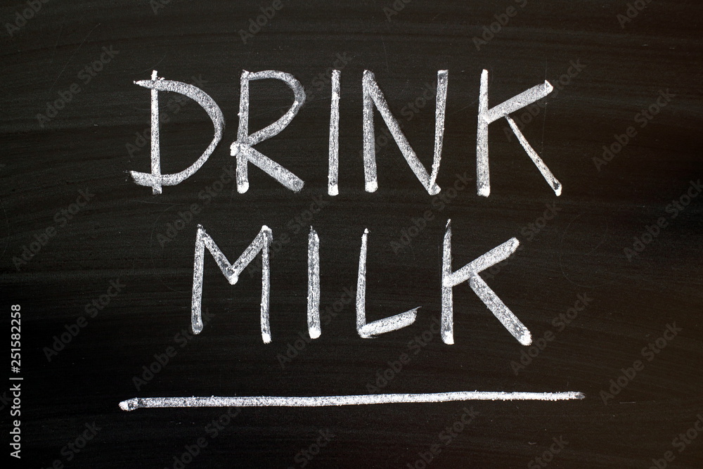 The words Drink Milk written by hand in white chalk on a blackboard as a reminder