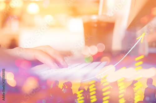 Business economic and technology working concept. Woman hand using keyboard double expose with graph money stock trading and blur people bokeh light background.