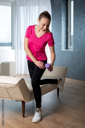 Hanteltraining gegen Verspannungen der Rückenmuskulatur, junge Frau in Sportkleidung zuhause