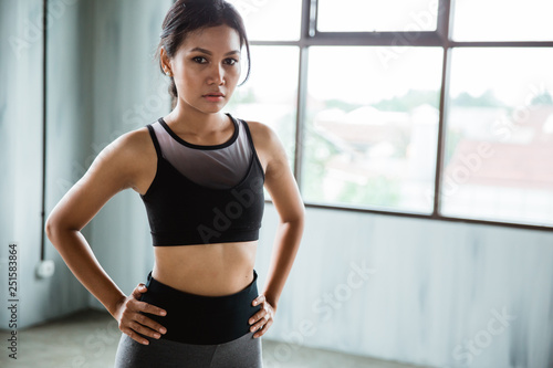 sporty woman with her hands on hips exercising looking at camera