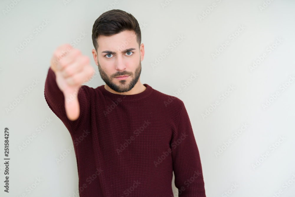 Young handsome man wearing a sweater over isolated background looking unhappy and angry showing rejection and negative with thumbs down gesture. Bad expression. Young handsome man wearing a sweater over isolated background looking unhappy and angry showing rejection and negative with thumbs down gesture. Bad expression.