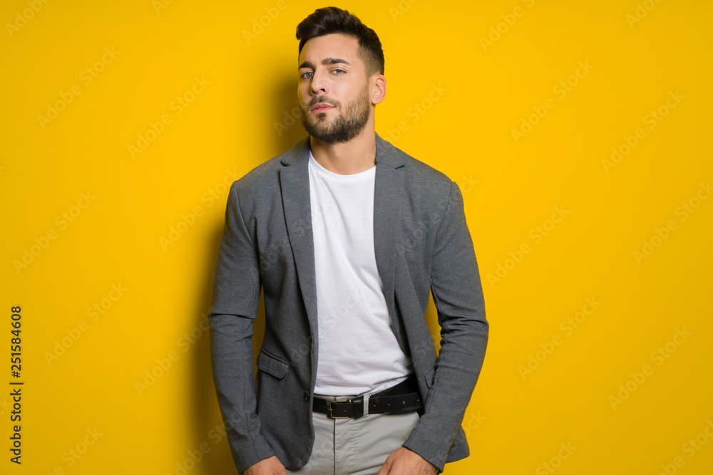 Young handsome man possing and modeling over yellow isolated background Young handsome man possing and modeling over yellow isolated background