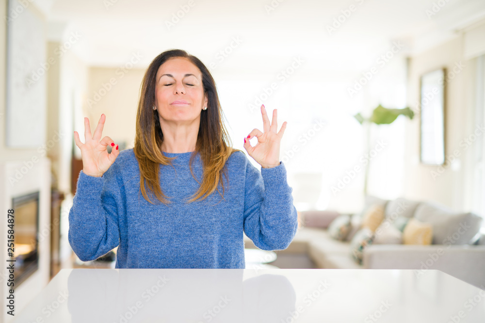 Beautiful middle age woman at home relax and smiling with eyes closed doing meditation gesture with fingers. Yoga concept.