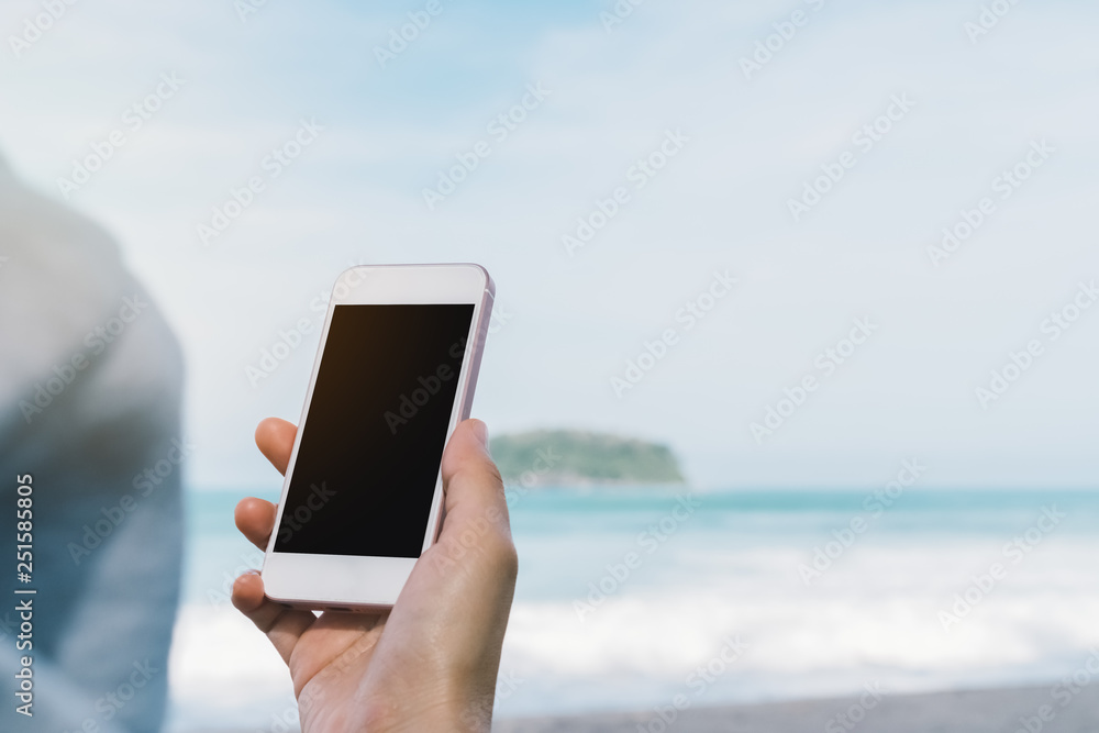 Copy space of woman hand using smart phone at beach background.