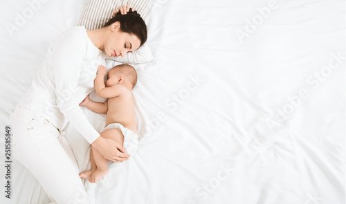 Young mom and her cute baby sleeping in bed