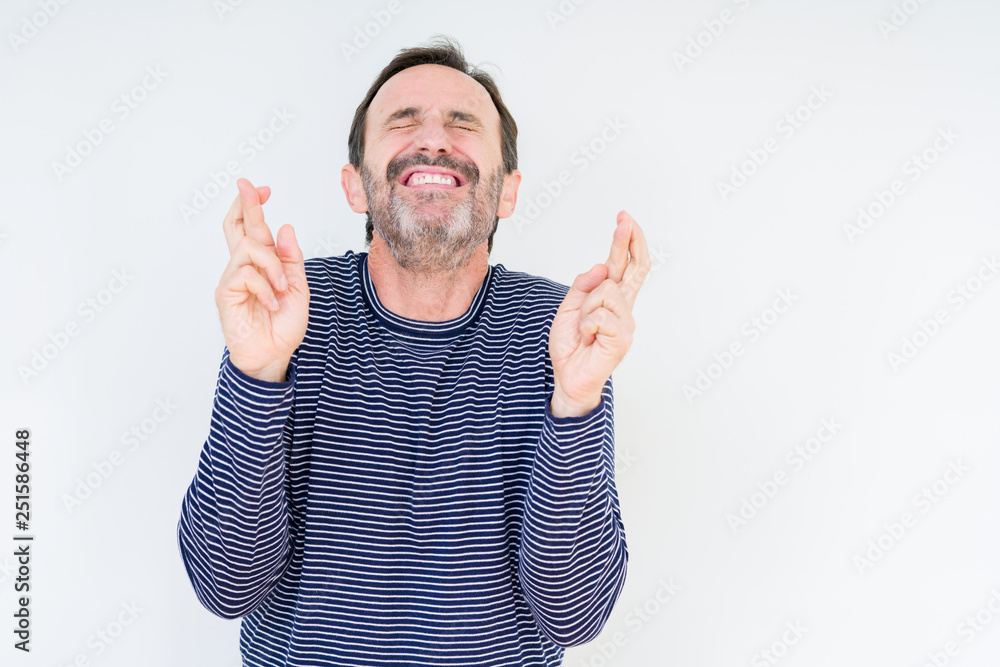 Handsome senior man over isolated background smiling crossing fingers with hope and eyes closed. Luck and superstitious concept. Handsome senior man over isolated background smiling crossing fingers with hope and eyes closed. Luck and superstitious concept.