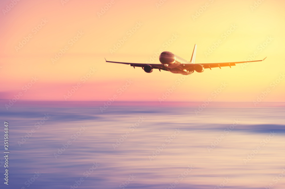 Airplane flying over blur tropical beach with smooth wave and sunset sky abstract background. Airplane flying over blur tropical beach with smooth wave and sunset sky abstract background.