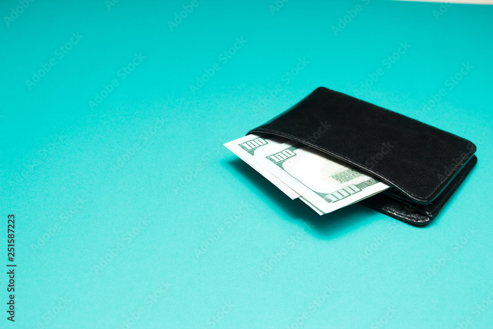 Black leather wallet with dollar bills on blue background. Men's purse with money bills Black leather wallet with dollar bills on blue background. Men's purse with money bills