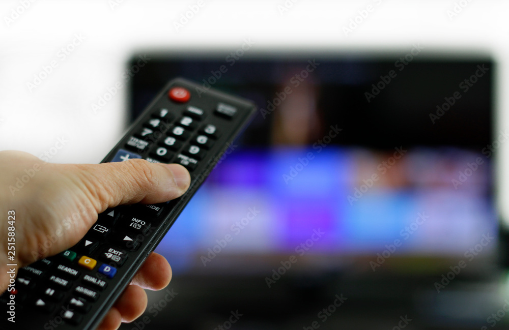 Hand holding remote control: Binge watching TV show Hand holding remote control: Binge watching TV show