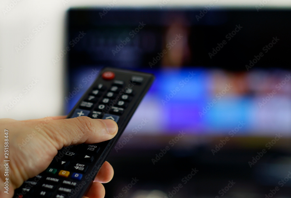 Hand holding remote control: Binge watching TV show Hand holding remote control: Binge watching TV show