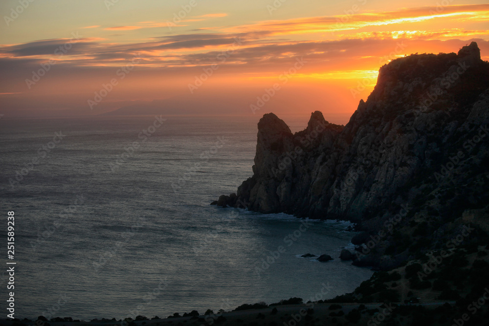 Coast of the Black Sea. Silhouette of a mountain near the sea against a beautiful sunset sky
