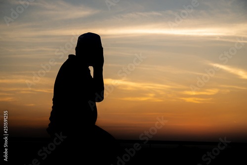 Silhouette Young asian muslim man praying on sunset,Ramadan festival concept